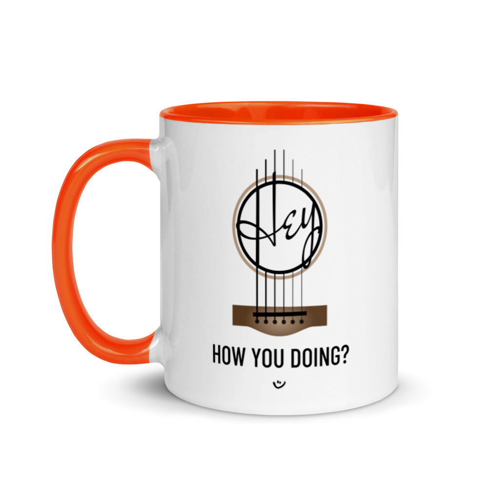 White mug with orange inside and handle, with 'Hey, How you doing? guitar design.